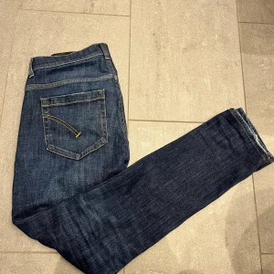 Mörkblå dondup jeans - Snygga mörkblå jeans från märket dondup. Jeansen har ett igensytt hål vid skrevet, hålet är igen sytt av en skräddare. Skick 8/10 modell: dondup George