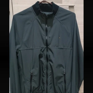 Svart jacka från Ralph Lauren - Snygg svart jacka från Ralph Lauren med dragkedja och broderad logotyp på bröstet. Jackan har en stilren design med långa ärmar och ribbade muddar. Perfekt för en casual look. Storlek S-M