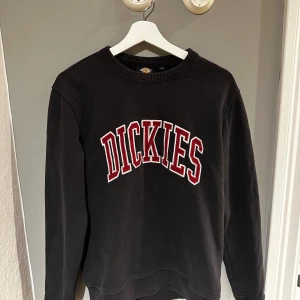 Svart tröja från Dickies - Säljer en svart tröja från Dickies med deras logga i rött och vitt på bröstet. Tröjan har långa ärmar och en rund halsringning. Perfekt för en avslappnad stil. Inte använd mycket.