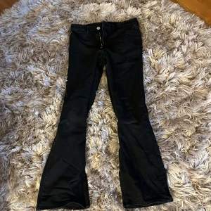 Svarta bootcut low-waist jeans - Snygga svarta byxor från H&M med flared leg och justerbar midja. Byxorna har låg midja och är perfekta för en trendig look. De är tillverkade i ett material som ger en skön passform och stil. Jag har använt de tre gånger och säljer för att de är för små😭tvättar och stryker innan de skickas!! Jag köpte de för 300kr men säljer för 150-200💗Priset kan diskuteras 