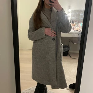 Grå kappa från Amisu - Säljer en stilren grå kappa från Amisu. Den har en klassisk design med knappar framtill och stora fickor. Perfekt för kyligare dagar och ger en elegant look. Passar bra till både vardag och mer uppklädda tillfällen. Säljer denna fina kappan. Den är knappt använd, väldigt fint skick och skönt material. Den är i storlek M.  Funkar att diskutera pris😊🥰