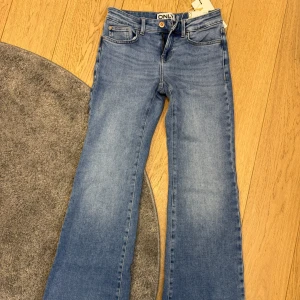 Ljusblå jeans från ONLY - Snygga ljusblå jeans från ONLY med en modern flared design. Byxorna har en låg midja och är tillverkade i denim. Prislappen är kvar och byxorna är aldrig använda!