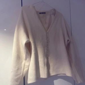 Shaped knitted cardigan - Säljer en stilren vit kofta från Gina Tricot i storlek M. Koftan har en v-ringad design med knappar framtill och långa ärmar. Perfekt för en elegant och avslappnad look.