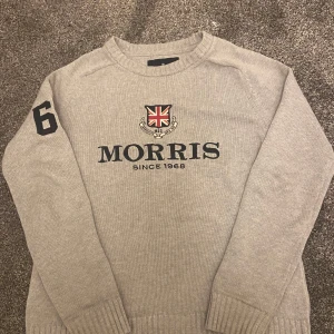 Morris grå tröja - Säljer en stilren grå stickad tröja från Morris med ett tryck av brittiska flaggan och texten 'Morris Since 1968' på framsidan. Tröjan har långa ärmar med siffran '68' tryckt på ena ärmen. Perfekt för en klassisk look.                                                                         Tröjan är storlek XS men passar också som S.               Skriv gärna för fler bilder eller frågor.                              Priset kan diskuteras vid snabb affär