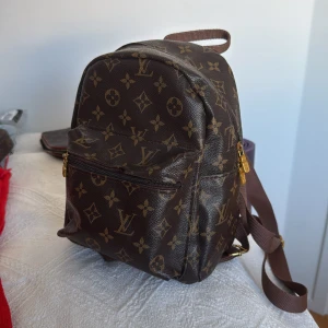 Ryggsäck i monogram  - En söt ganska liten/medelstor ryggsäck i monogram i läderimitation. 