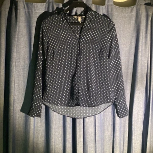 Svart mönstrad skjorta - Säljer en snygg svart skjorta med ett coolt vitt mönster. Skjortan har långa ärmar och knappar framtill. Perfekt för både vardag och fest! 🖤