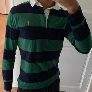 Säljer en snygg och klassisk randig pikétröja från Ralph Lauren. Perfekt för en lite finare och stilren look. Plagget är i storlek 14-16 år och den passar mig bra som är 177 cm lång. Nästan oanvänd.