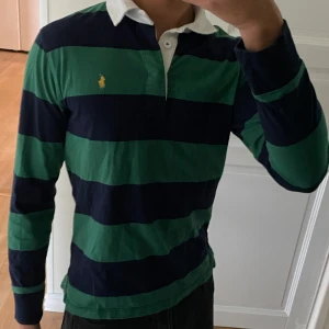 Randig pikétröja från Ralph Lauren - Säljer en snygg och klassisk randig pikétröja från Ralph Lauren. Perfekt för en lite finare och stilren look. Plagget är i storlek 14-16 år och den passar mig bra som är 177 cm lång. Nästan oanvänd.