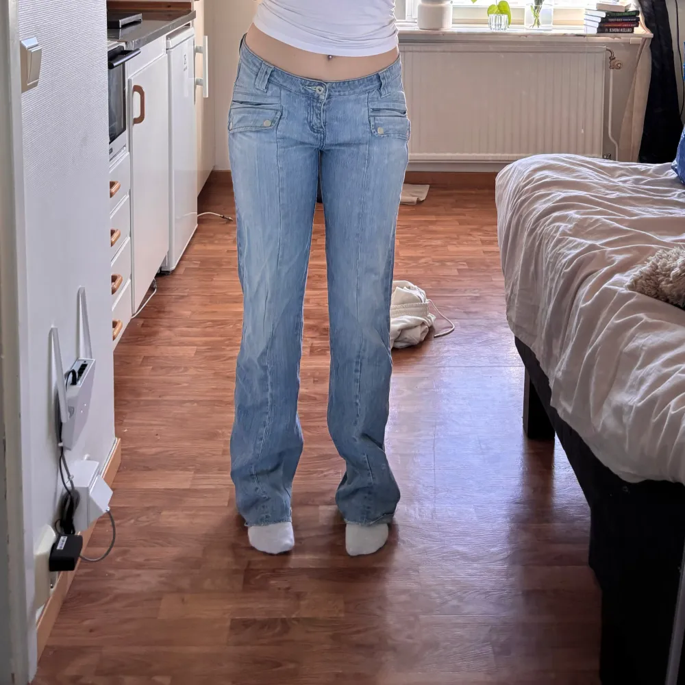 Säljer ett par snygga ljusblå jeans med låg midja och bootcut-stil. De har coola detaljer som knappar på fickorna och en klassisk dragkedja. Är i mycket bra skick, kan vara lite slitet nere vid fötterna då de är för långa på mig men annars super bra😍. Farkut & Housut.