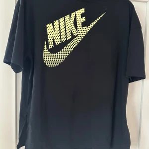 Svart Nike t-shirt med gul logga - Säljer en svart Nike t-shirt i storlek XS. Den har en cool gul logga på framsidan som verkligen poppar! Perfekt för vardagsbruk eller träning. T-shirten är i bra skick och redo för en ny ägare. Passa på att köpa den nu! 🖤💛