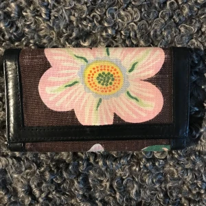 Josef Frank, Svenskt Tenn plånbok - Josef Frank, Svenskt Tenn fin plånbok med ett stort blommönster i rosa på brun botten. Plånboken har svarta läderdetaljer och flera fack för kort och mynt. Lite sliten på tyget. Tyvärr blir dessa plånböcker det. Hämtas på Hägerstensåsen eller ök 👛