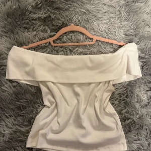 Vit offshoulder topp - Säljer en superfin vit offshoulder topp som är perfekt för sommaren. Köpt på Gina tricot men använt bara en gång. Den har en elegant och stilren design med en bred krage som ger en snygg look. 
