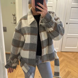 Rutig overshirt i ull - Rutig höstjacka i ull med bälte. Perfekt till höst & vinter med dragkedja. Använd 1 gång, nyskick och finns ej att få tag på längre! 