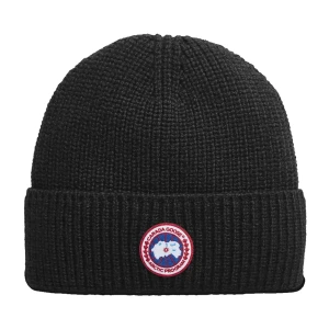 Svart stickad mössa från Canada Goose - Snygg svart stickad mössa från Canada Goose med ett broderat märke framtill. Perfekt för kalla dagar och ger en stilren look. Mössan är ribbad och har en klassisk passform.