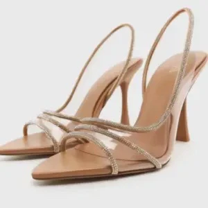 Beige klackskor med transparenta remmar! ALDRIG ANVÄNT - Eleganta beige klackskor med spetsig tå och transparenta remmar dekorerade med pärlor. Perfekta för en stilren look.