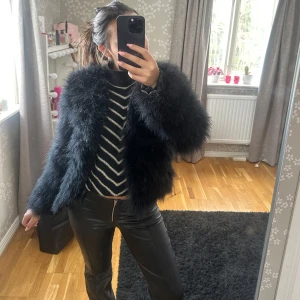 Svart pälsjacka från DM - Säljer en fluffig och trendig svart pälsjacka från DM. Jackan har en kort och chic design med långa ärmar, perfekt för att ge en lyxig touch till din outfit. Den är idealisk för kyligare dagar och ger en statement-look. 