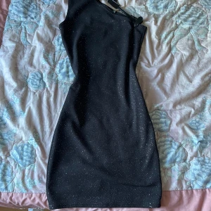 Svart glittrig klänning  - Snygg svart klänning från PrettyLittleThing med glittrande detaljer ✨ One-shoulder design och ärmlös. I nyskick, storlek XS,34  passar även S!🖤
