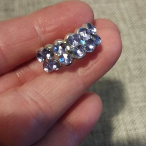 Silverfärgad ring med lila stenar - Snygg silverfärgad ring dekorerad med flera rader av lila glittrande stenar. Perfekt för att ge en färgklick till din outfit. Ringen har en justerbar design för att passa olika storlekar.