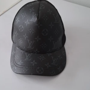 Lv keps - Snygg svart keps med lv.Framsidan är i ett glansigt material medan baksidan har ett nät för ventilation. Perfekt för en stilren look.
