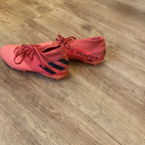 Fotbollsskor adidas nemesis - Det är röda/rosa adidas nemesis fotbollsskor storlek 42 och en halv är o bra skicka inga skador bara lite använda 