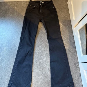 Svarta Bootcut Jeans - Gina Tricot  - Ett par väldigt fina svarta midwaist jeans från Gina Tricot. De har använts ungefär 5 gånger max och är i mycket bra skick. Jag säljer de pga att de är lite för långa på mig (är 155 cm) och för att de blivit för små i midjan. Bortsett från det är byxorna normala i storleken. Innerbenslängden är ca 76 cm och midjemåttet är ca 32 cm. De är i storlek 34. Rekommenderar de verkligen då de passar till allt!🤍