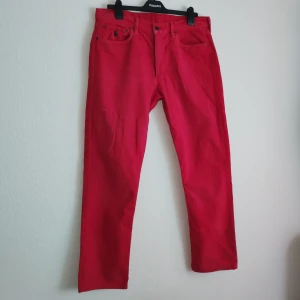 Röda byxor från Ralph Lauren - Snygga röda byxor från Ralph Lauren med klassisk design. Byxorna har en rak passform och är tillverkade i ett slitstarkt material. Perfekta för att ge en färgklick till din outfit.