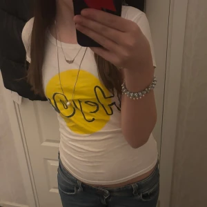 Vit heyou t-shirt - Säljer en vit t-shirt med en stor gul cirkel och svart text på framsidan. T-shirten har en rund halsringning och korta ärmar. Perfekt för en avslappnad stil. Passar bra till jeans eller shorts, jättebekväm och köpt för några år sedan på heyou