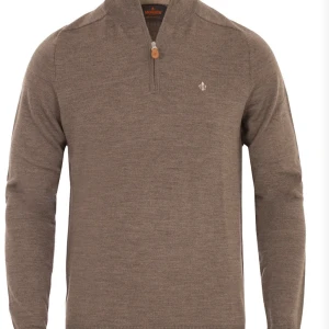 Brun tröja med dragkedja från Morris - Snygg brun tröja från Morris med en liten dragkedja vid halsen och ett diskret broderat emblem på bröstet. Perfekt för en stilren look. Tröjan har långa ärmar och är tillverkad i ett mjukt material. Använd högst 5 gånger. Fint skick nypris 1800kr