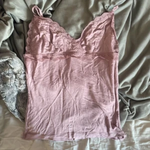 Rosa linne med spetsdetaljer - säljer ett sött rosa linne med spetsdetaljer vid halsringningen och axelbanden. linnet har en v-ringad design och är perfekt för varma dagar. det är tillverkat i ett mjukt material som känns skönt mot huden, tror inte jag använt den alls. xs men passar större storlekar oxå!💕