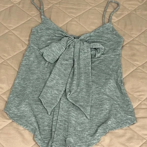 Grå topp med knyt - Snygg grå topp med smala axelband och en knytning framtill från Gina Tricot. Haft på den ca 2 gånger