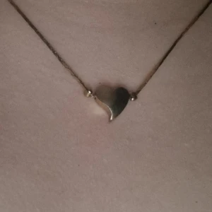 Halsband med hjärta i guld - Elegant halsband med ett litet hjärta i guld. Perfekt för att lägga till en subtil touch av elegans till din stil. Kedjan är tunn och smidig, vilket gör den bekväm att bära dagligen.
