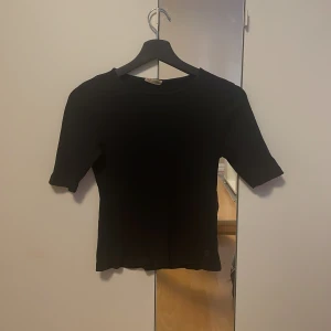 Svart ribbad topp från Ü - Säljer en  svart ribbad topp från Ü. Toppen har längre ärmar och säljer då jag inte använder längre 🖤