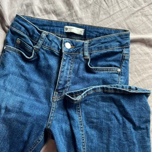 Blå jeans från Gina Tricot - Snygga blå jeans från Gina Tricot med klassisk femficksdesign och knappgylf. Perfekta för en avslappnad stil. Märket 'perfect jeans' syns på baksidan. Midrise skulle jag säga och mått kan skrivas privat. Utsvängda 