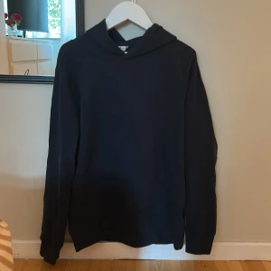 Mörkblå hoodie - Säljer en stilren mörkblå hoodie med långa ärmar. Perfekt för en avslappnad look. Den har en klassisk design med huva och är tillverkad i ett mjukt och tunt material. Den är strl 146-152 men den passar 158 (då sitter den tight).