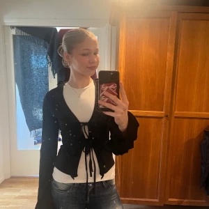 Svart omlottopp från Gina Tricot - Säljer en helt ny snygg svart omlottopp från Gina Tricot. Toppen har långa ärmar och fina volangdetaljer längs kanterna. Den är knytbar framtill vilket ger en stilren look. Perfekt för att uppgradera garderoben! 🖤toppen är alltså oanvänd så den är i nytt skick. 