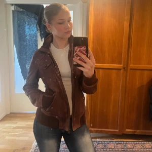 Brun skinnjacka från edc - Säljer en snygg brun skinnjacka från edc med dragkedja och ribbade muddar. Jackan har långa ärmar och två bröstfickor med knappar. Perfekt för höst och vår! Den är i äkta läder och har varit väl omhändertagen💕