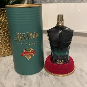 Jean Paul Gaultier Le Beau Le Parfum - Säljer en elegant parfym från Jean Paul Gaultier, Le Beau Le Parfum. Flaskan är formad som en manlig torso i en stilren svart och grön gradient. Den kommer i en unik grön metallcylinder med guldtext och detaljer. Perfekt för den som vill ha en distinkt och lyxig doft.