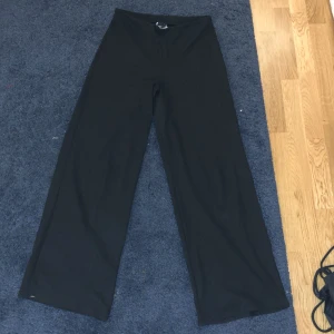 Svarta byxor från Gina Tricot - Snygga svarta kostymbyxor från Gina Tricot med en loose passform. Byxorna har en hög midja och är tillverkade i ett mjukt material som ger en bekväm känsla. Byxorna är bootcut och helt galet snygga. Perfekta för en stilren look. De är i storlek S och på mig som är M så sitter de tajt runt låren men bootcut vid smalbenen😍😍