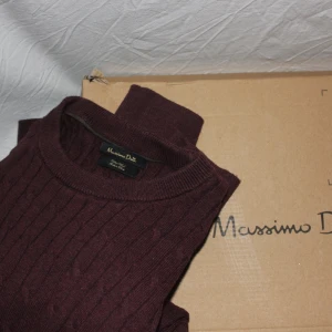 Vinröd stickad tröja från Massimo Dutti - Snygg vinröd stickad tröja från Massimo Dutti. Tröjan har ett diskret kabelstickat mönster och rund halsringning.