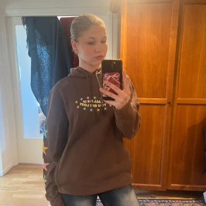 Brun hoodie med stjärnor och text - Säljer en Tyler the creator hoodie i färgen brun med texten 'CALL ME IF YOU GET LOST' på bröstet. Ärmarna har färgglada stjärnor i rosa, blått och gult. Perfekt för en avslappnad stil. Jag har knappt använt hoddien sen jag köpte den, därmed så är hoddien i mycket bra skick.💞