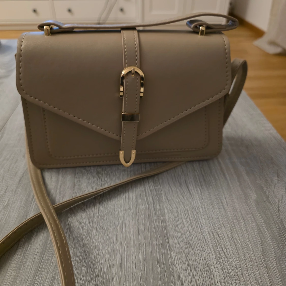 Oanvänd beige axelväska med gulddetaljer