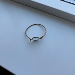 Guldarmband med oval detalj - Elegant guldarmband med en enkel och stilren design. Armbandet har en oval detalj i mitten som ger en modern touch. Perfekt för att komplettera din look med en subtil men sofistikerad accessoar.