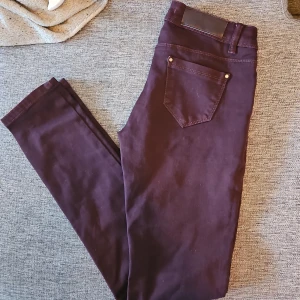 Mörklila jeansbyxor - Snygga mörklila jeansbyxor med en klassisk femficksdesign. Byxorna har en smal passform och är perfekta för en stilren look. De är tillverkade i ett mjukt och stretchigt material för extra komfort.