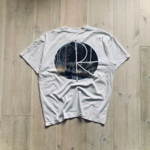 Vit t-shirt från Polar Skate Co. - Säljer en vit t-shirt från Polar Skate Co. med ett stilrent tryck på bröstet och ett stort, konstnärligt motiv på ryggen. T-shirten är kortärmad och tillverkad i bomull, perfekt för en avslappnad stil. En fläck vid midjan men annars inga defekter!