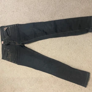 Mörkblå jeans från Replay - Snygga mörkblå jeans från Replay med klassisk femficksdesign och knappgylf. Perfekta för en stilren look. Märkesdetaljer syns på bakfickan och linningen.