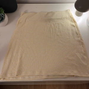 Gul och vit rutig kjol från Nelly - Säljer en söt gul och vit rutig kjol från Nelly i storlek XS. Kjolen har en enkel och stilren design med ett mjukt material som känns skönt mot huden. Perfekt för varma dagar! Inga lappar kvar men aldrig använd. Skriv för bilder med den på