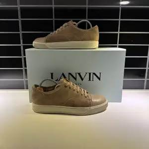 Snygga beige sneakers från Lanvin med en stilren design. Skorna har snörning och en vit sula som ger en modern touch. Tillverkade i skinn för en lyxig känsla. Perfekta för en avslappnad men elegant stil.