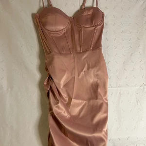 Champagnefärgad klänning från Shein - Elegant champagnefärgad klänning från Shein i satin med smala axelband och en figurnära passform. Klänningen har en korsettliknande överdel med vadderade kupor och sömdetaljer som ger en lyxig känsla. Perfekt för en speciell kväll! ✨klänningen är knälång