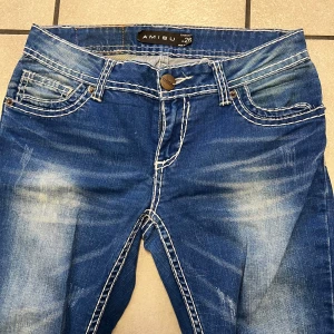 Blå jeans från Amisu - Snygga blå jeans från Amisu med en klassisk femficksdesign och kontrasterande vita sömmar. De har en knapp och dragkedja framtill och en lätt slitning för en trendig look. Perfekta för en avslappnad stil.