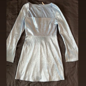 Ljusblå klänning med långa ärmar - Elegant ljusblå klänning med långa ärmar och en dragkedja i ryggen. 